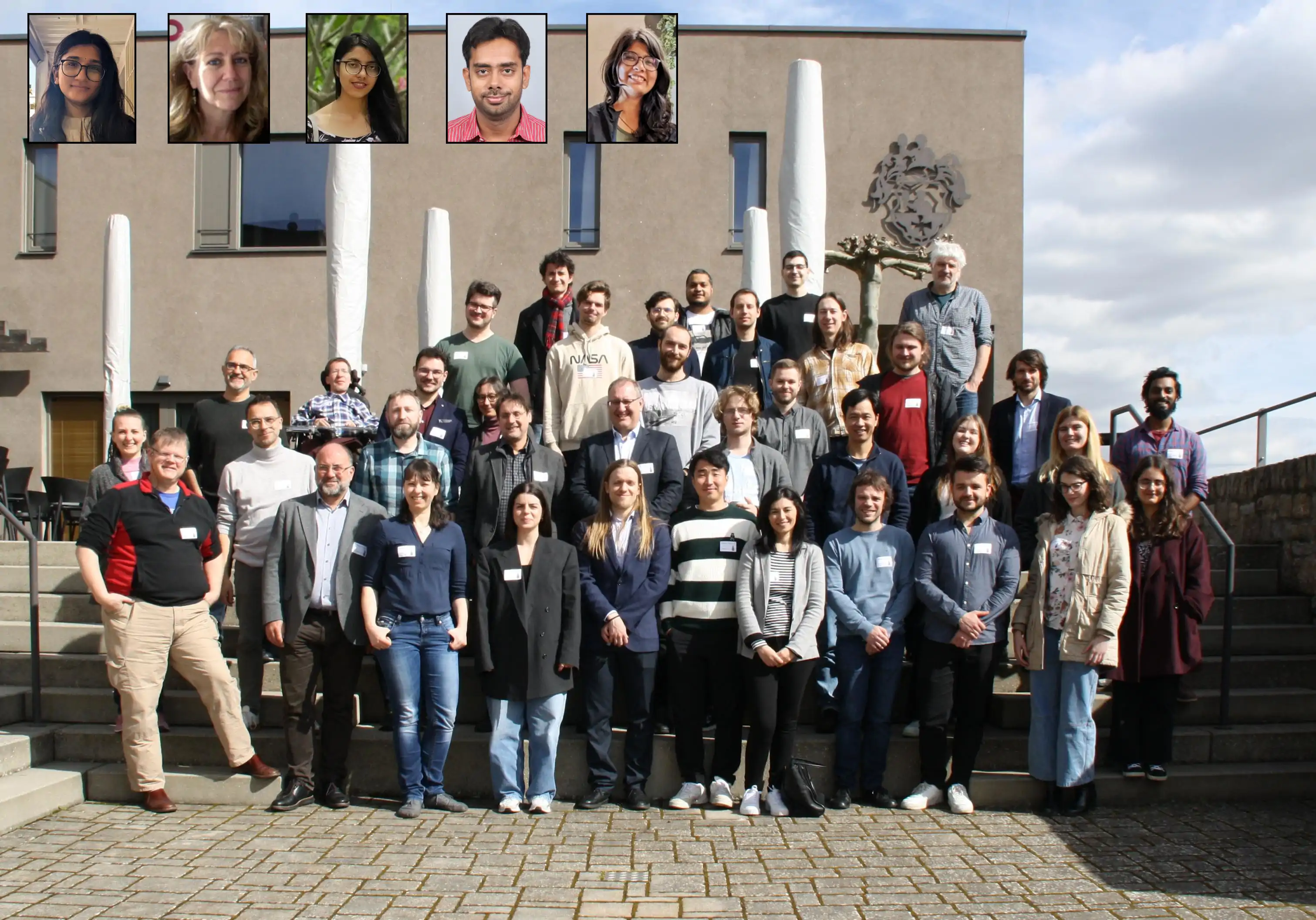 Group picture of the annual assembly 2024 with the remote participants shown in the inset pictures. Group picture of the annual assembly 2024 with the remote participants shown in the inset pictures. About 45 people are standing on a stairs in front of a building. Most people are of age of approximately 25 to 40 years with few persons that are older. Four inset images show remote participants of the meeting.